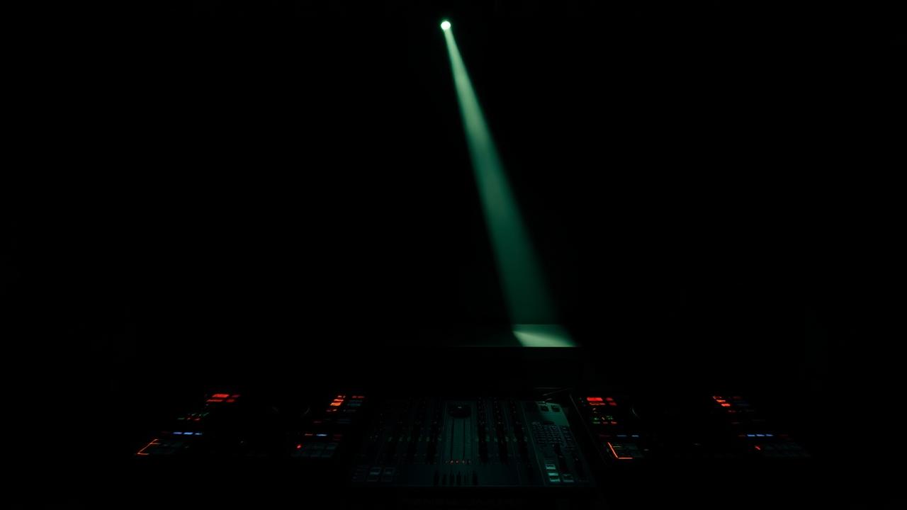 Dark DJ booth lit by a single narrow beam of light