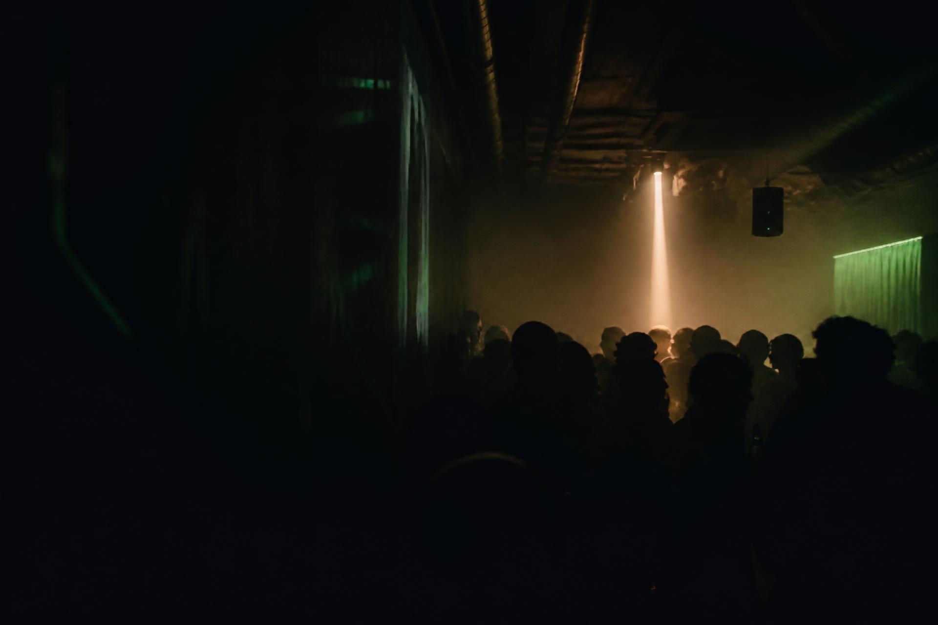 Crowd in a dark club lit by a single beam of light